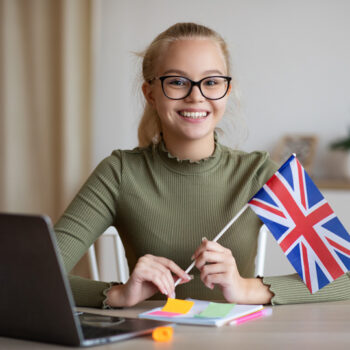 smiling-girl-with-flag-of-great-britain-using-lapt-RRKLTVE